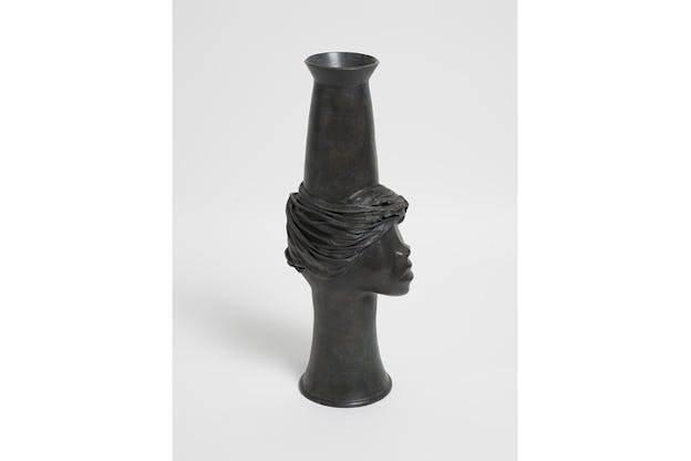 A cylindrical black statue with its middle carved in a face.