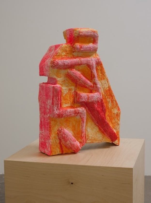 Close-up of a candy pink and orange abstract and geometric sculpture slightly resembling one or two human figures.