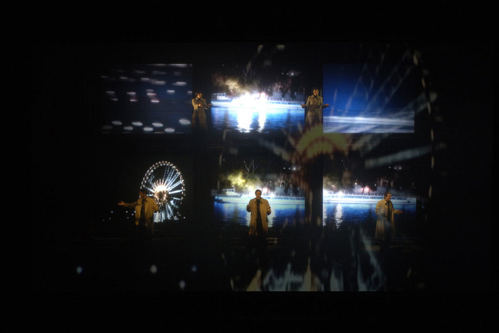 Six scenes are in front of a black background. The scenes show a performer in a yellow shirt in front of abstract blue and black backgrounds. The scene in the lower left corner shows this performer in front of a ferris wheel. 