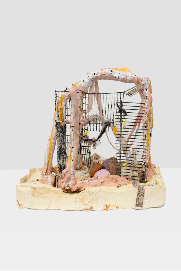 A ceramic sculpture comprised of salmon pink, white, tan, and orange arches embedded with metal grating on a thick clay base.