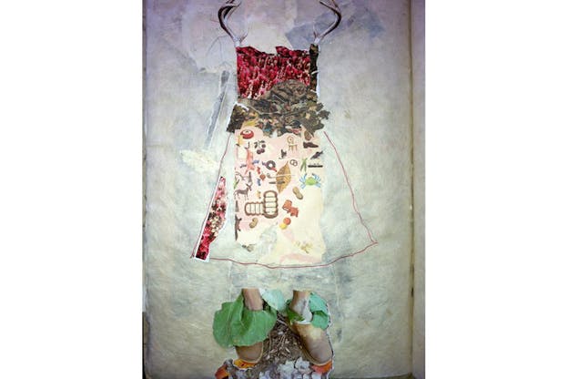 Fragments of multi-patterned material collaged into the outline of a dress on wax-resembling paper. Deer antlers emerge from the dress sleeves and at the bottom, feet wrapped in nasturtium leaves and slippers stand on a patch of exposed dirt.