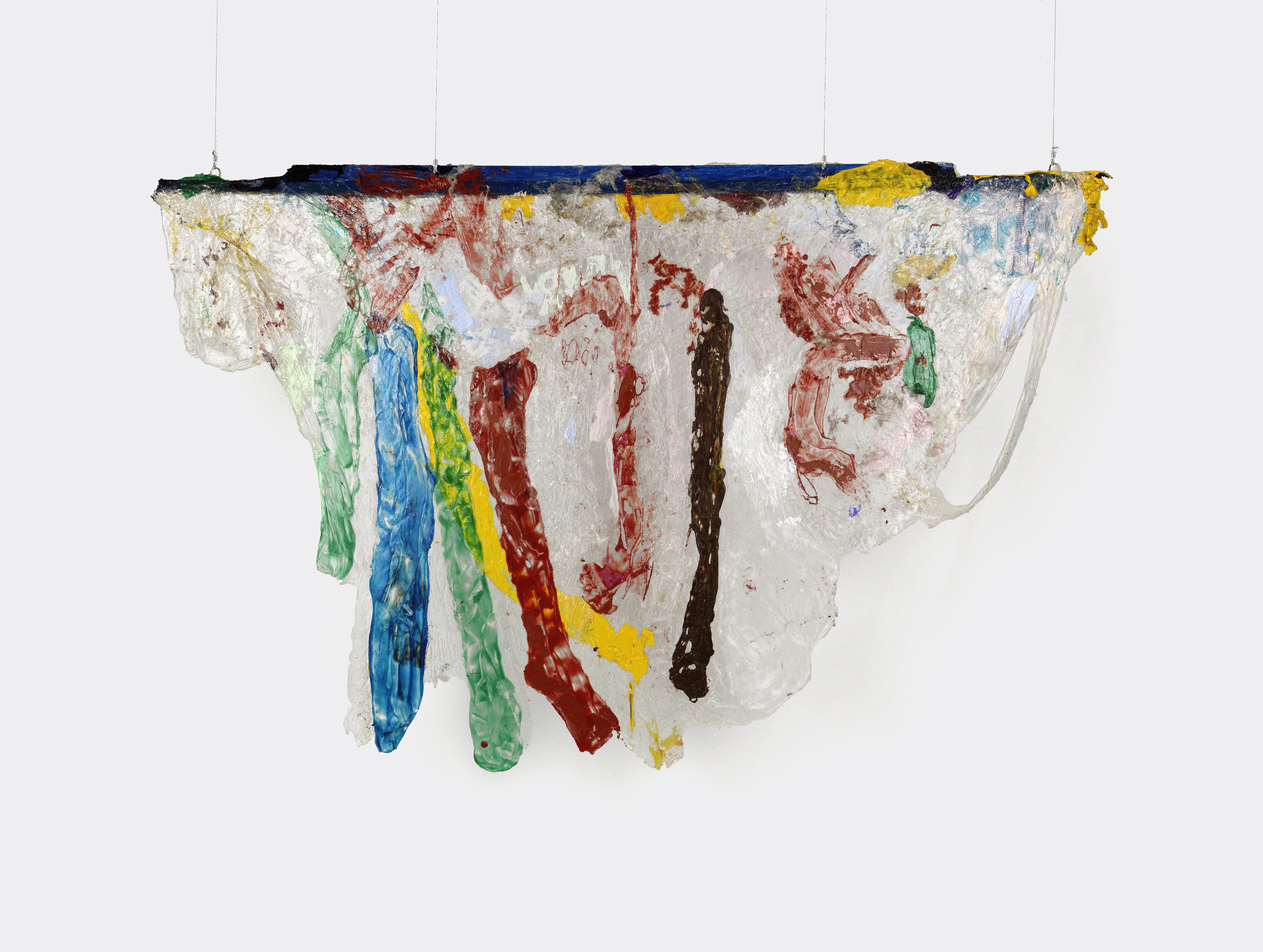 A hanging sculpture of primarily opaque white acrylic draped over a thin plank of wood that is painted dark blue. Stripes of green, blue, yellow, red, and brown run vertically along the draped white acrylic, resembling drips. Areas of red and yellow and speckles of blue appear throughout other areas of the piece. The bottom edges of the draped acrylic are smooth and sloping.