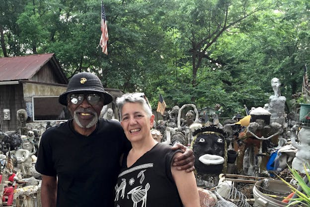 Beglarian and Dr. Charles Smith smiling, his arm wrapped around her shoulder, in front of an outdoor collection of sculptures. 