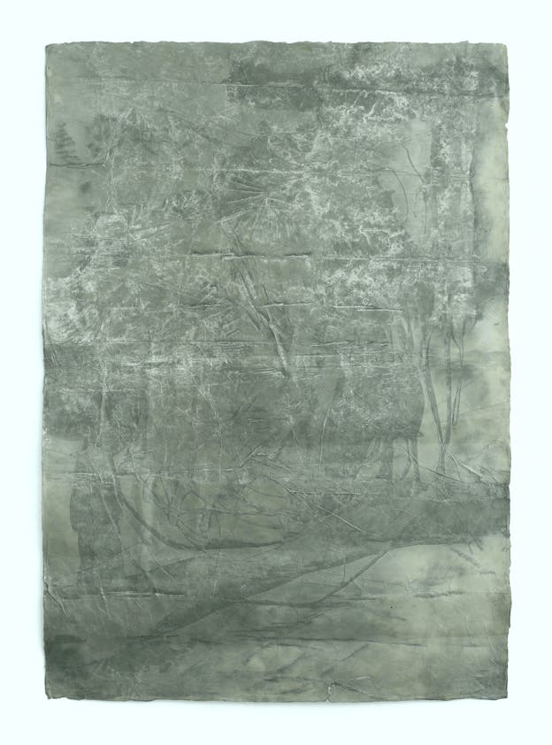 A single sheet of paper marked with folds and crinkles and painted with fields of gray, white, and sage green.