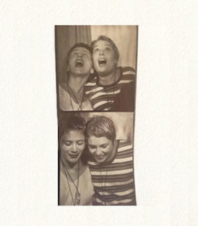 A photoboth film style portrait of two people. In the photo on the top, they both look up. In the photo on the bottom, they both look down. The person on the left wears a sweatshirt and necklace. The person on the right wears a horizontally striped shirt. Both performers have short hair.  