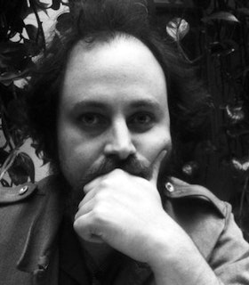 Black and white portrait of Zach Layton with his face resting in his hand.