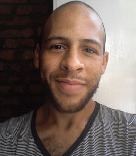 Portrait of Will Rawls smiling at the camera and wearing a thinly striped black and white shirt.