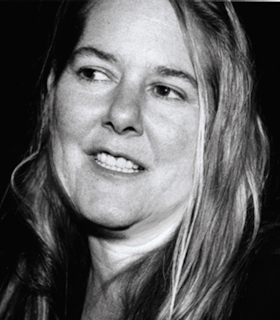 A black and white portrait of RoseAnne Spradlin. She has medium length hair and is glancing towards her right.