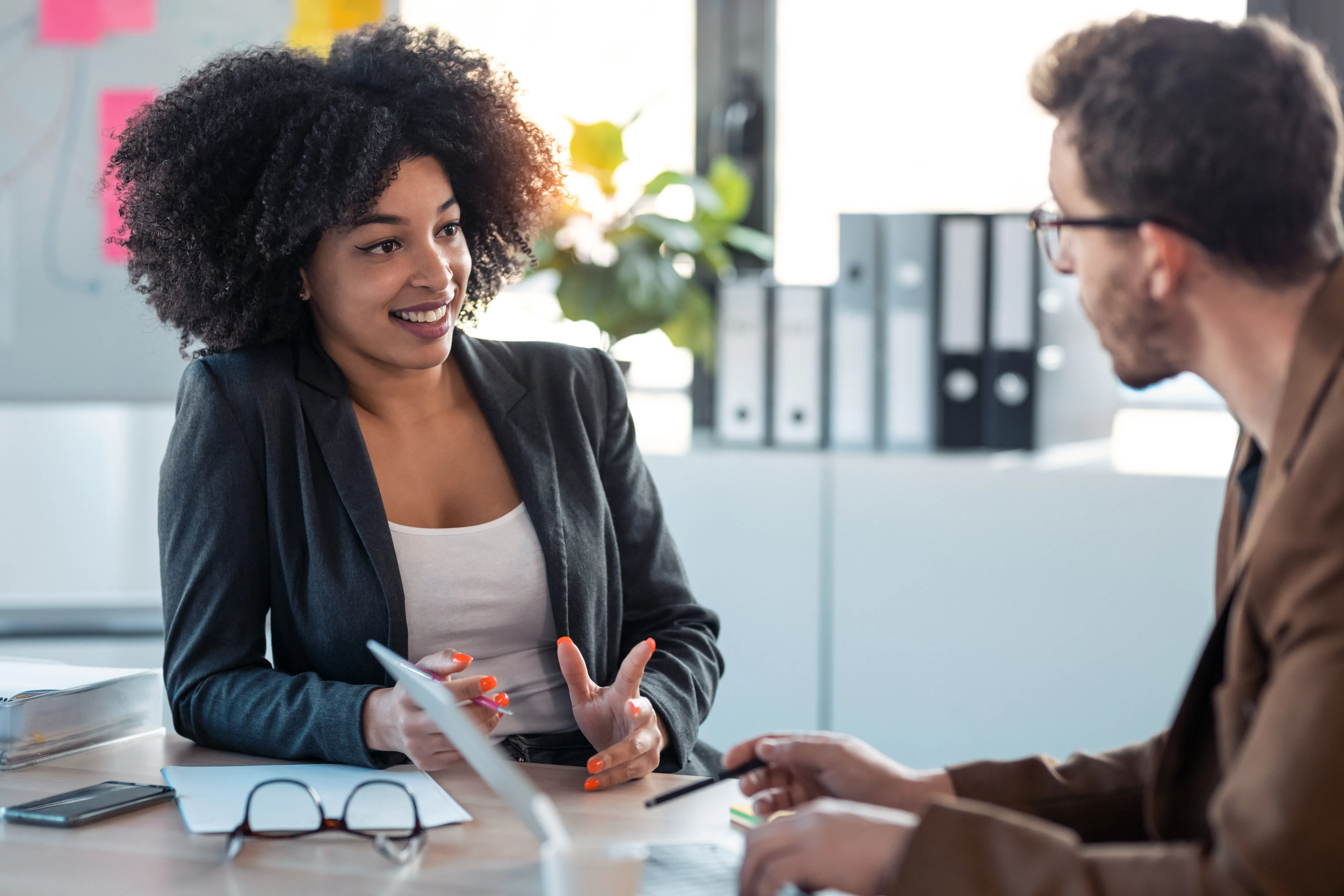 AI generated image of Two smart business people working together with laptop while talking about job news in the office 