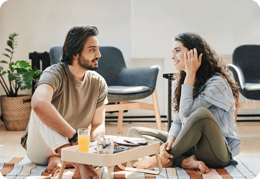 Couple sitting on the floor and having breakfast while talking about insurance