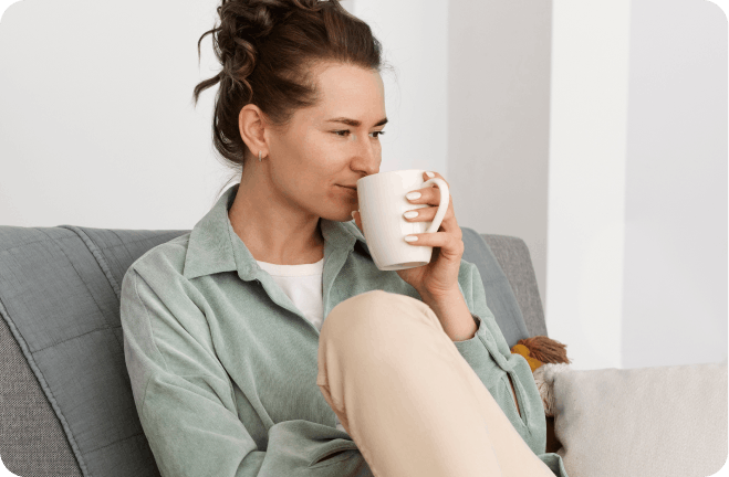 Woman with a cup on a couch.