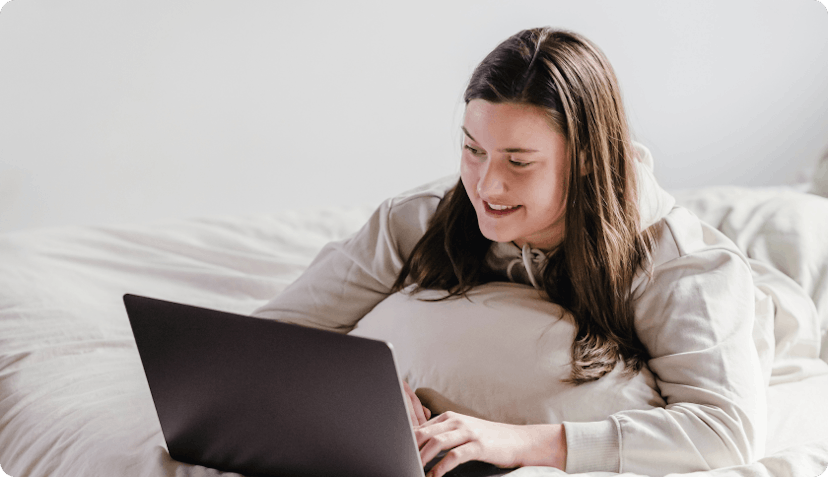 Woman switching to private health on her laptop while laying in bed