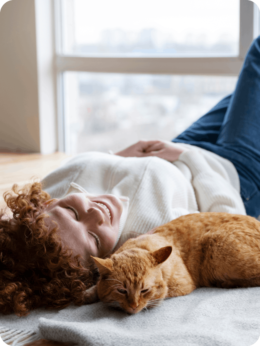 Woman laying with her ginger cat after veterinary visit