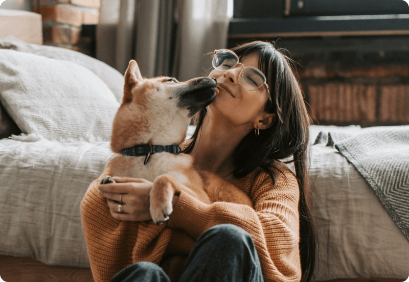 Woman enjoying her dog's affection after signing up for dog liability insurance