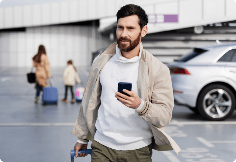 Man holding his phone at the airport parking lot