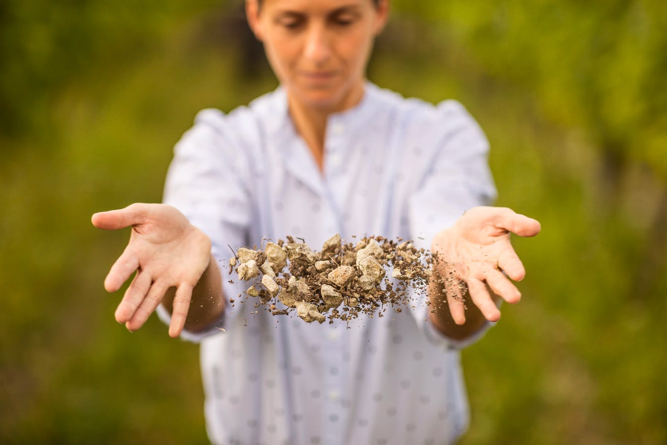 une femme tenant en lévitation un mélange de cailloux et de petits morceaux de terre et bois