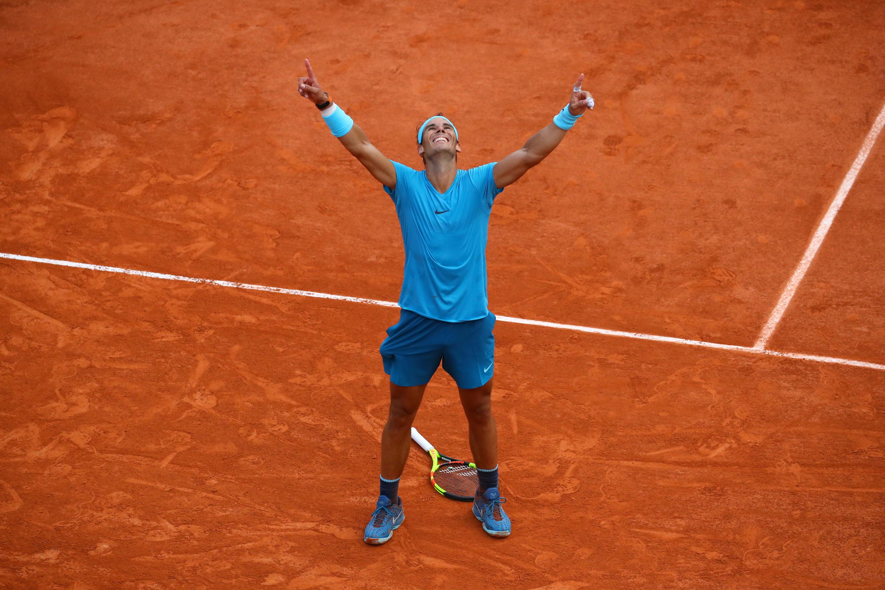 Rafael Nadal smiling and pointing the fingers to the sky as he wins Roland-Garros 2018