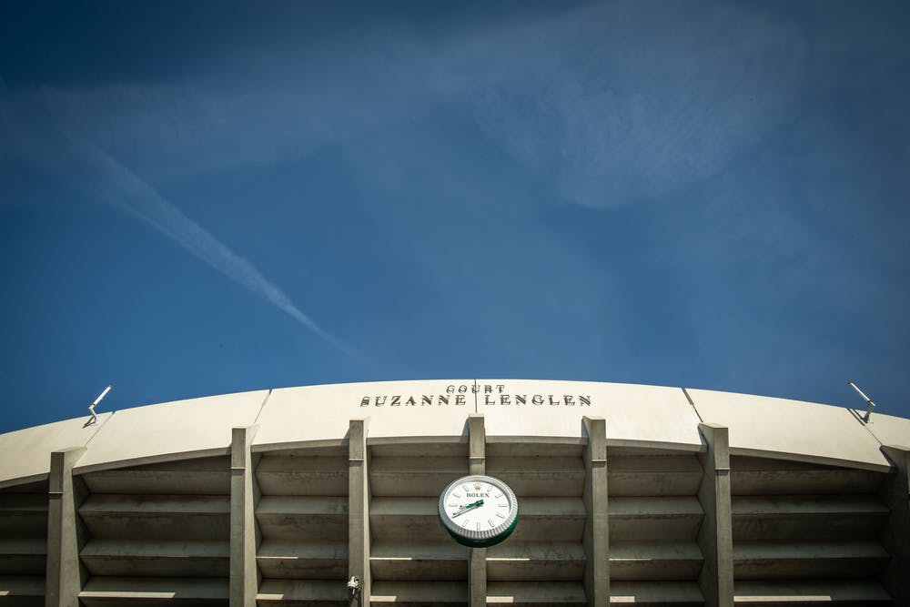 Ciel bleu sur le court Suzanne Lenglen et l'horloge Rolex avant le débutd e Roland-Garros 2019.