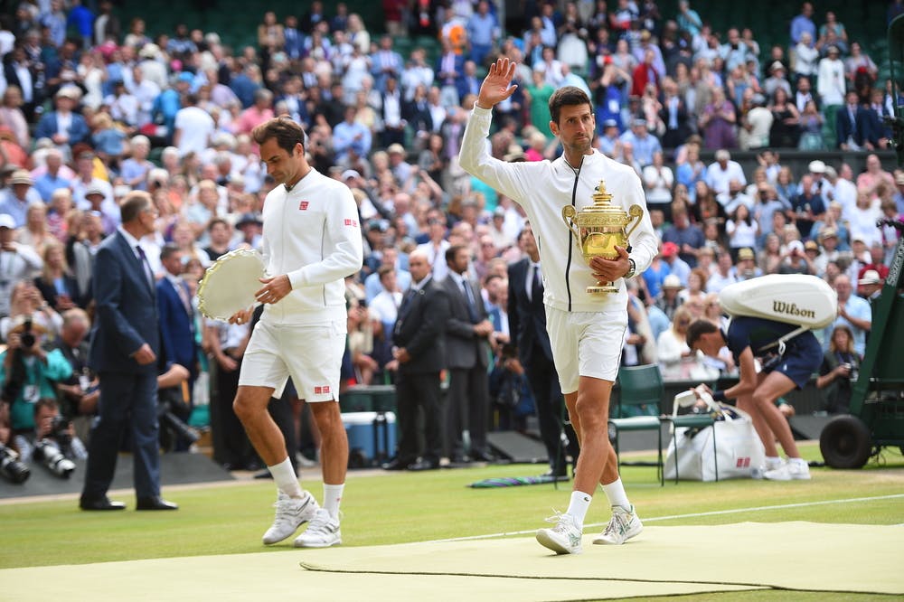 Novak Djokovic walking next to Roger Federer both holding their trophies Wimbledon 2019