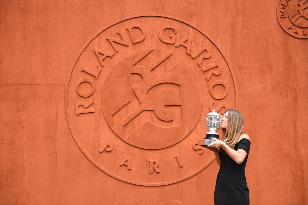 Simona Halep kissing the Roland-Garros 2018 trophy in front of the RG18 clay wall