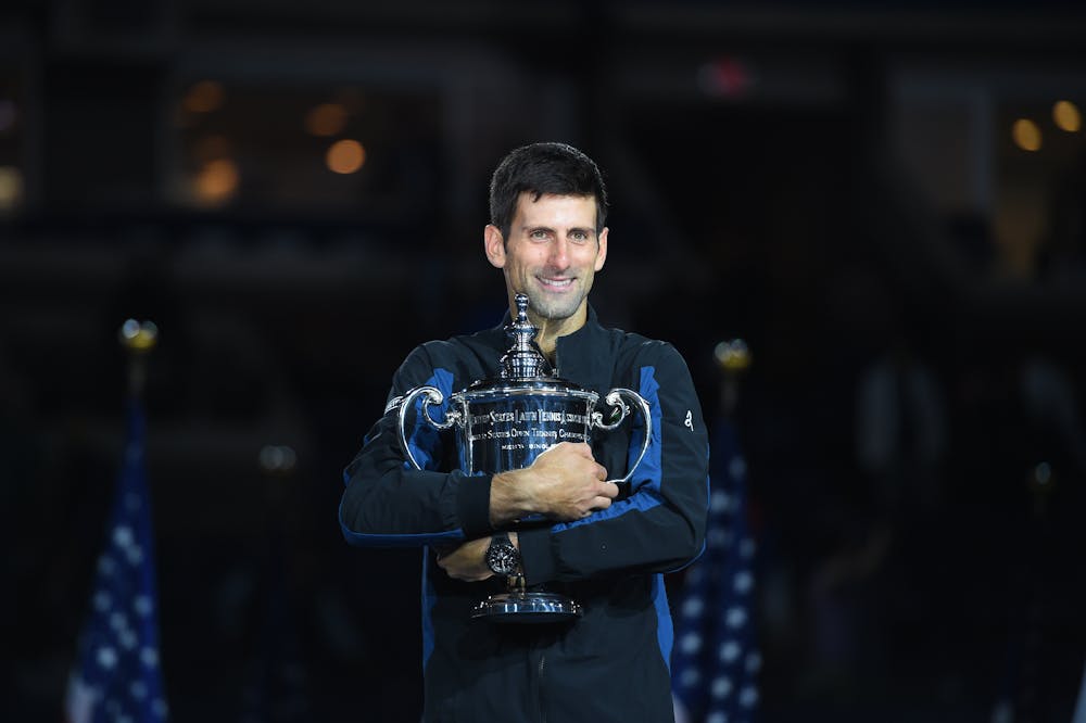 Novak Djokovic smiling while holding the trophy US Open 2018
