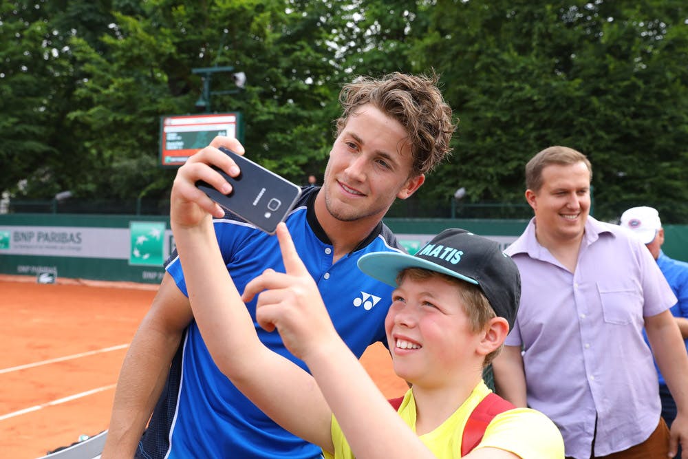 Casper Ruud poses with a fan after winning his second-round qualifying match at Roland-Garros 2018.