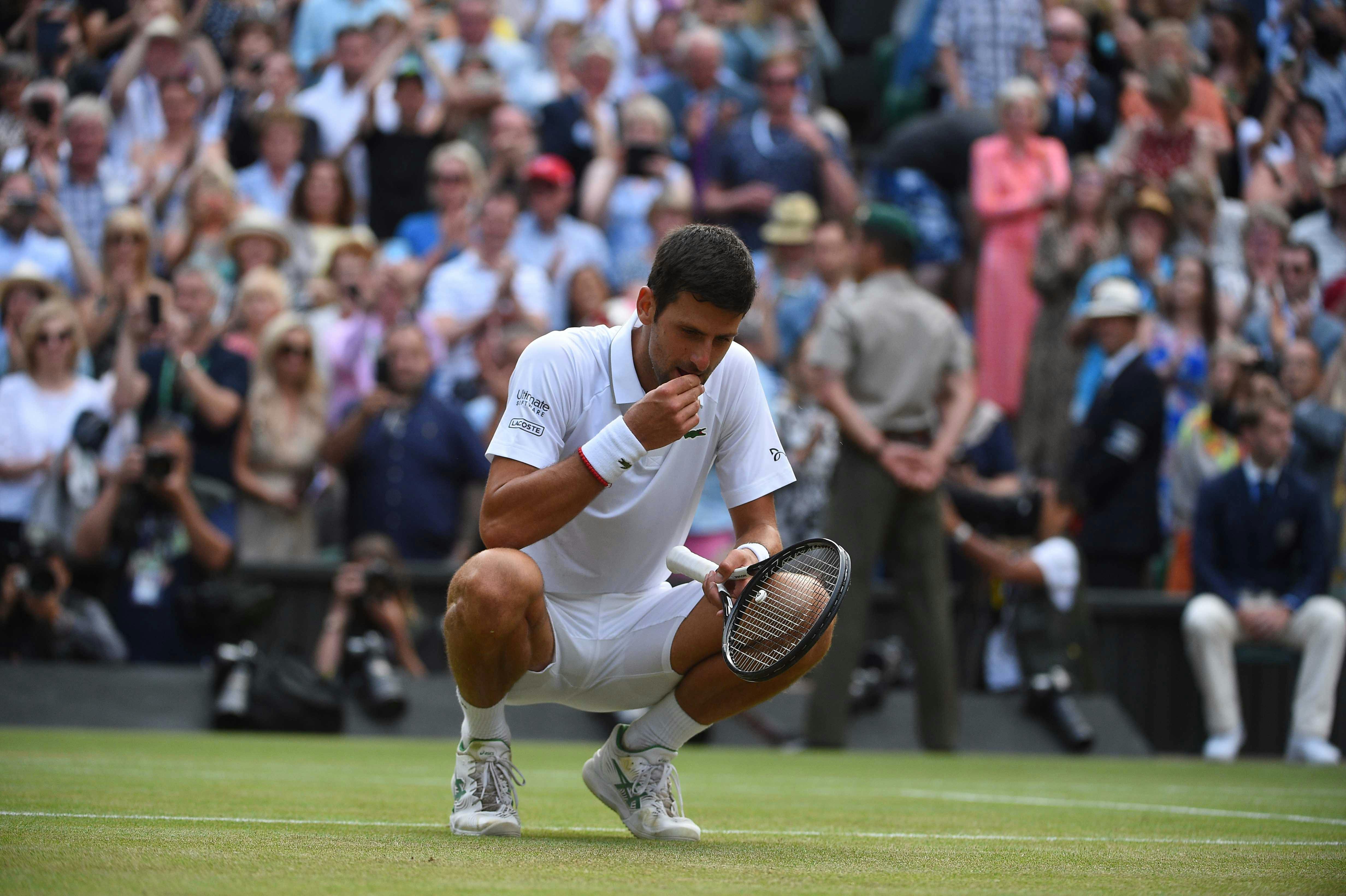 Novak Djokovic tasting the grass at Wimbledon 2019