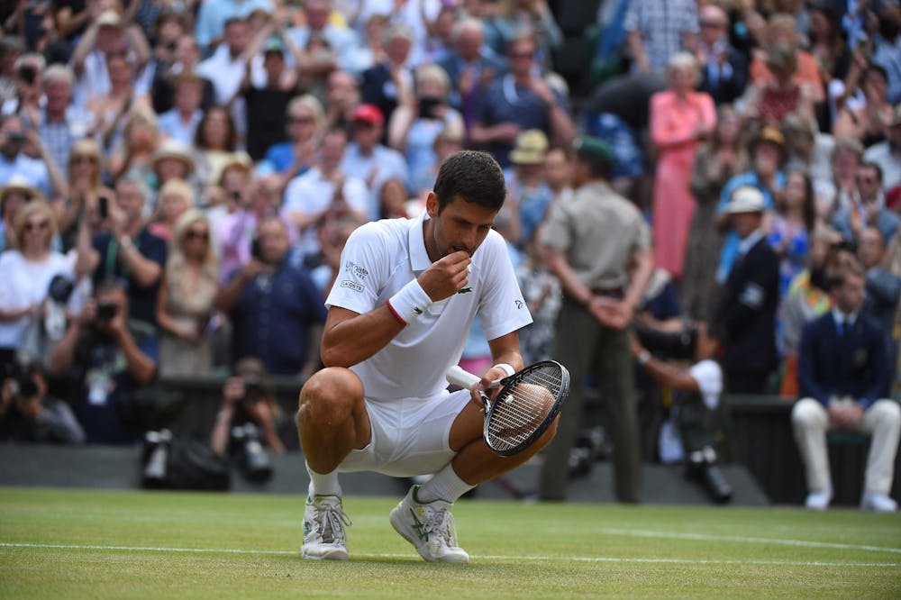 Novak Djokovic tasting the grass at Wimbledon 2019