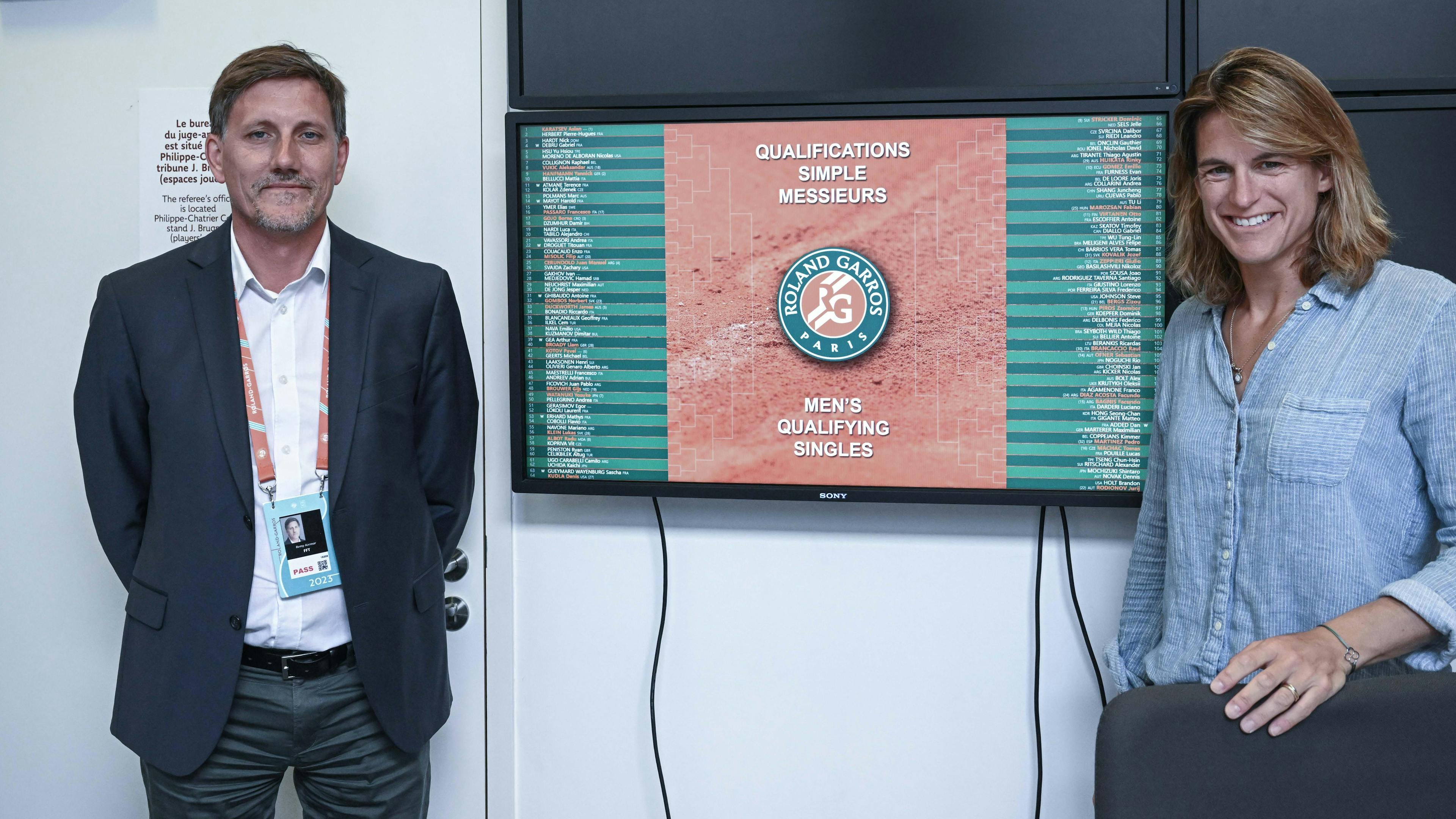 Le juge-arbitre Rémy Azémar et la directrice du tournoi Amélie Mauresmo devant le tableau des qualifications.