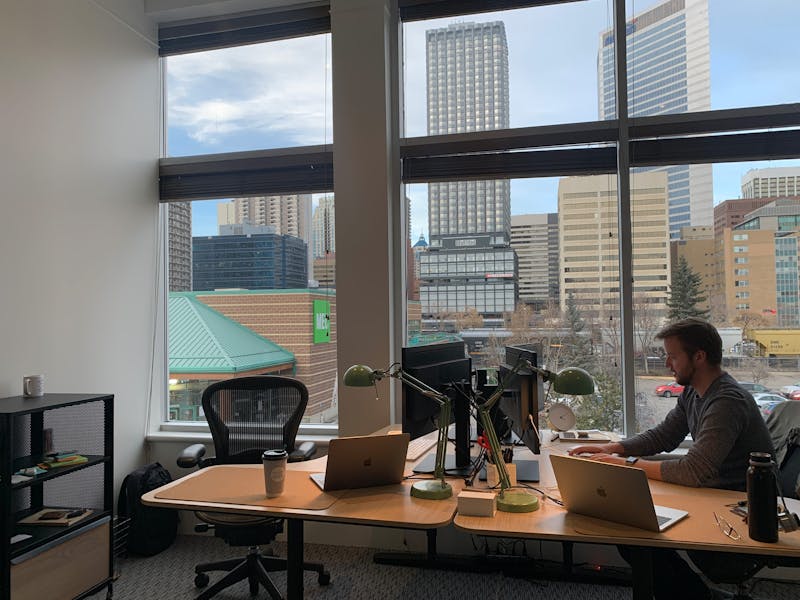 Brett working at desk with downtown Calgary behind