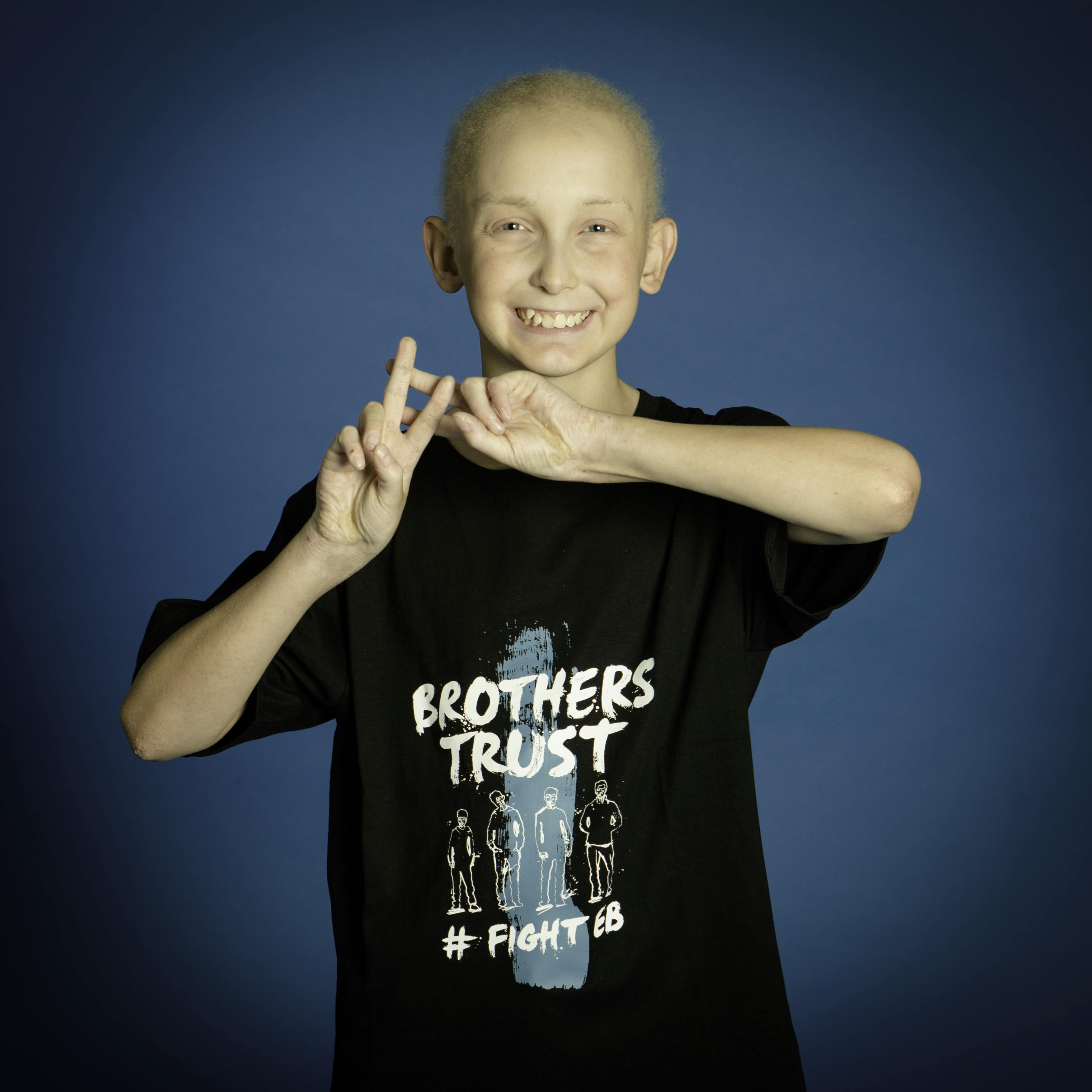 A girl in a black t-shirt making a hashtag sign with her hands.