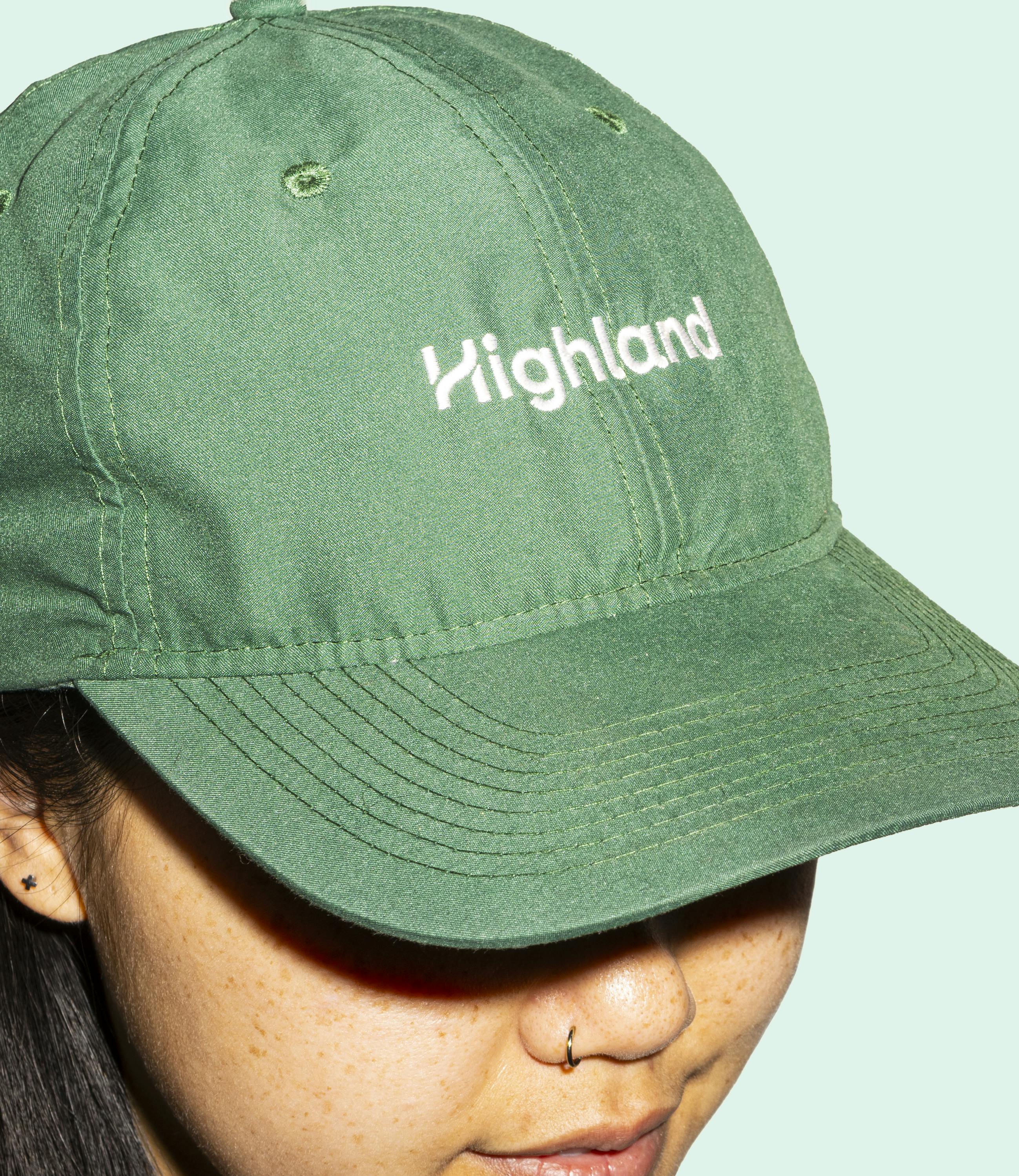 The Highland logo embroidered on a green hat.