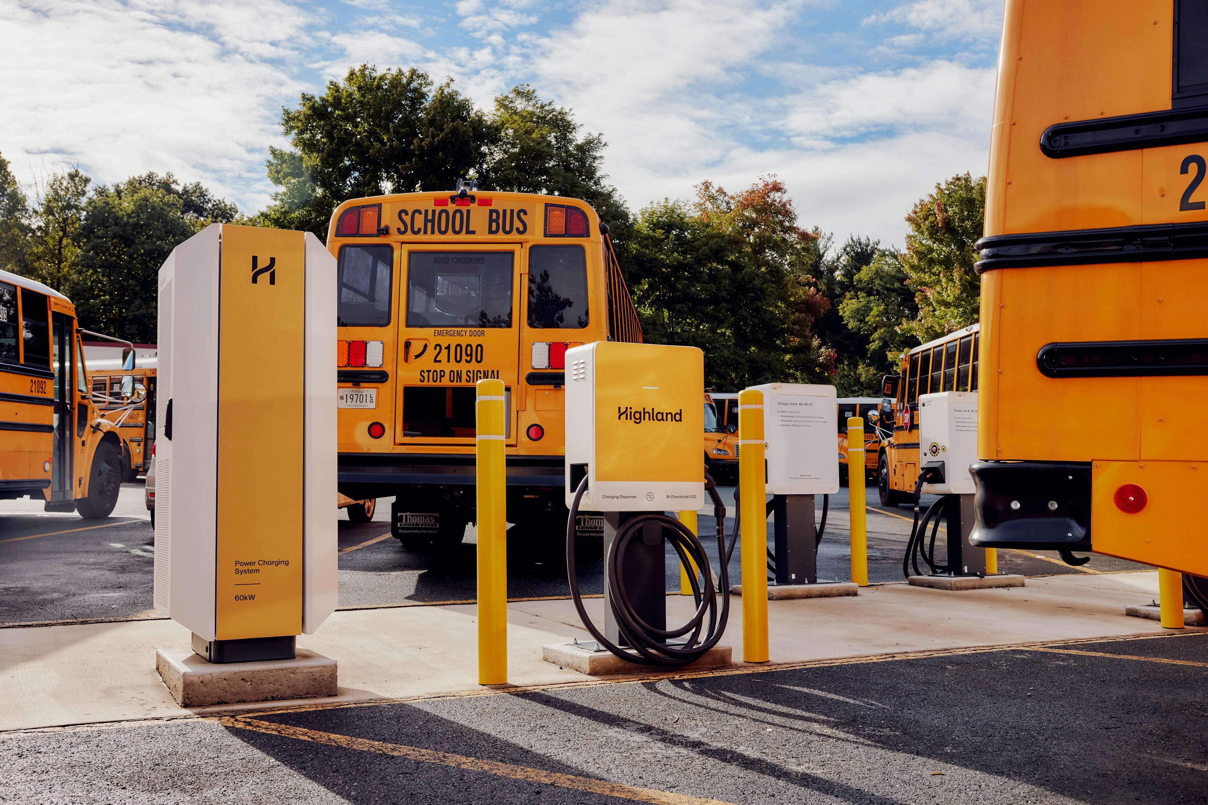 A parking lot full of Highland electric school buses in their charging stations.