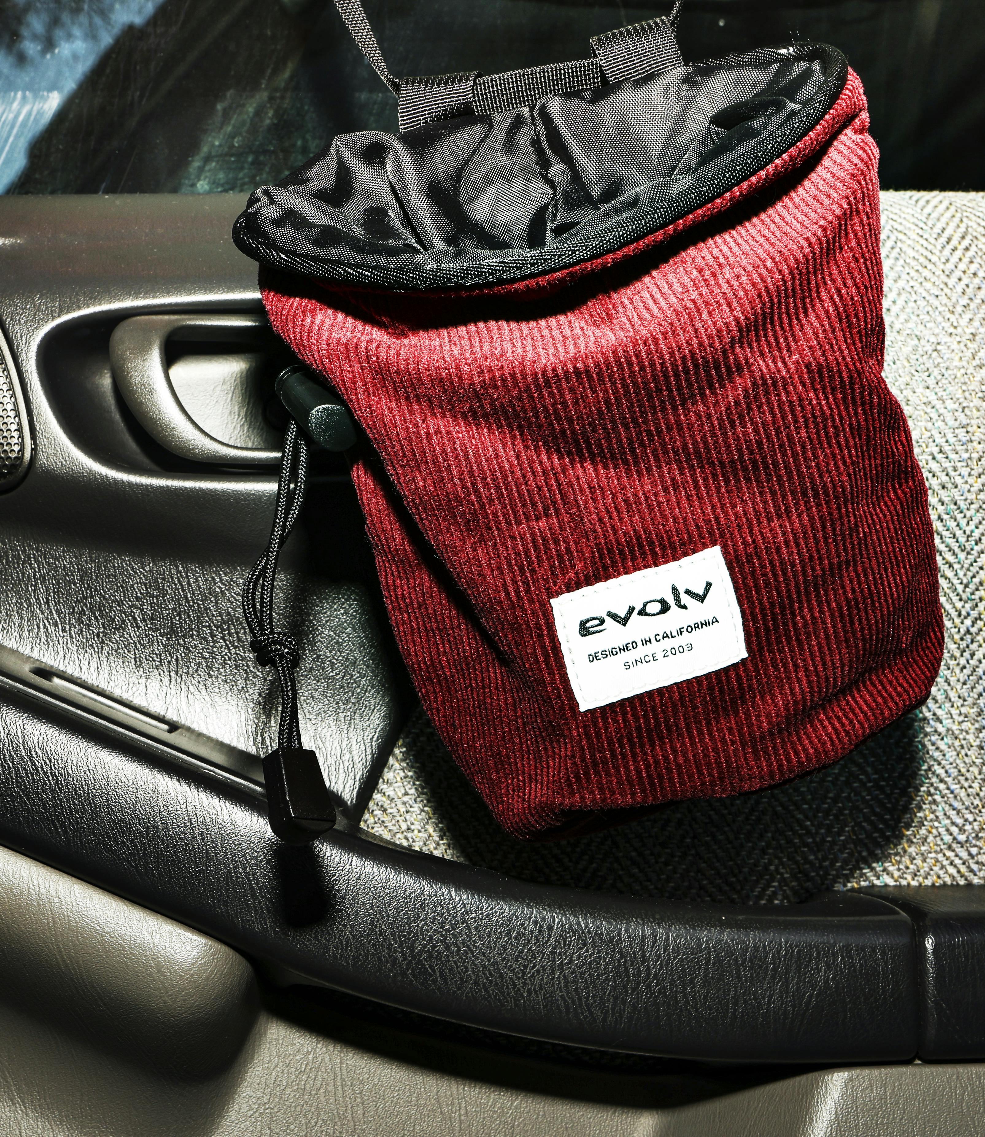 A corduroy evolv chalk bag hangs inside of a car door.