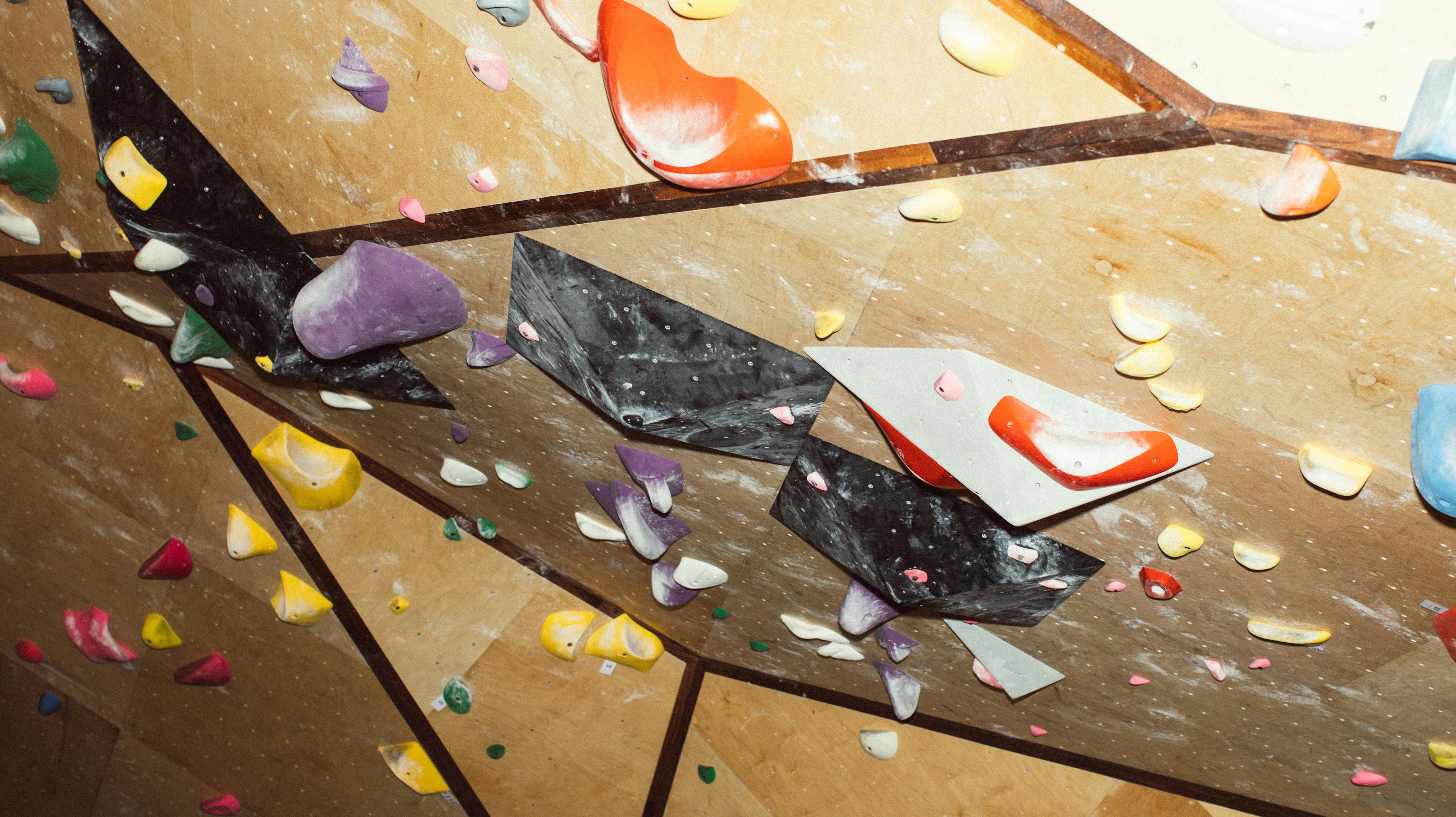 An indoor climbing wall shows holds covered in chalk.