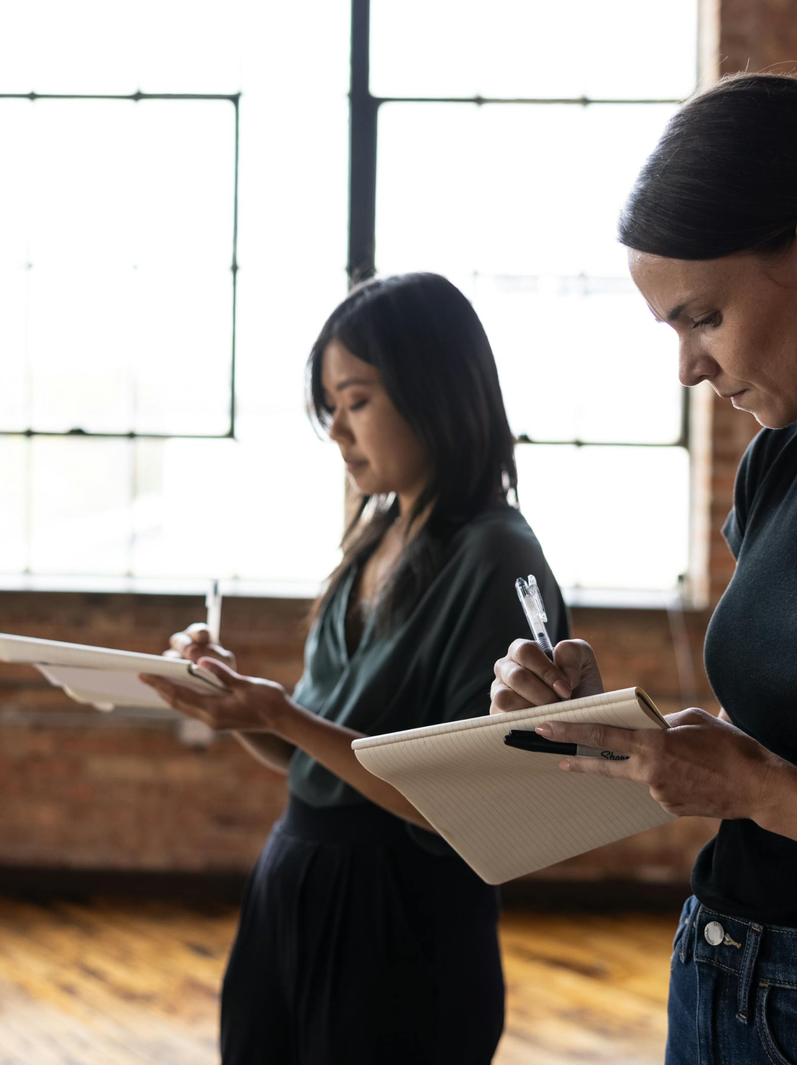 Two Figure employees write down notes on a notepad in a Figure workshop.