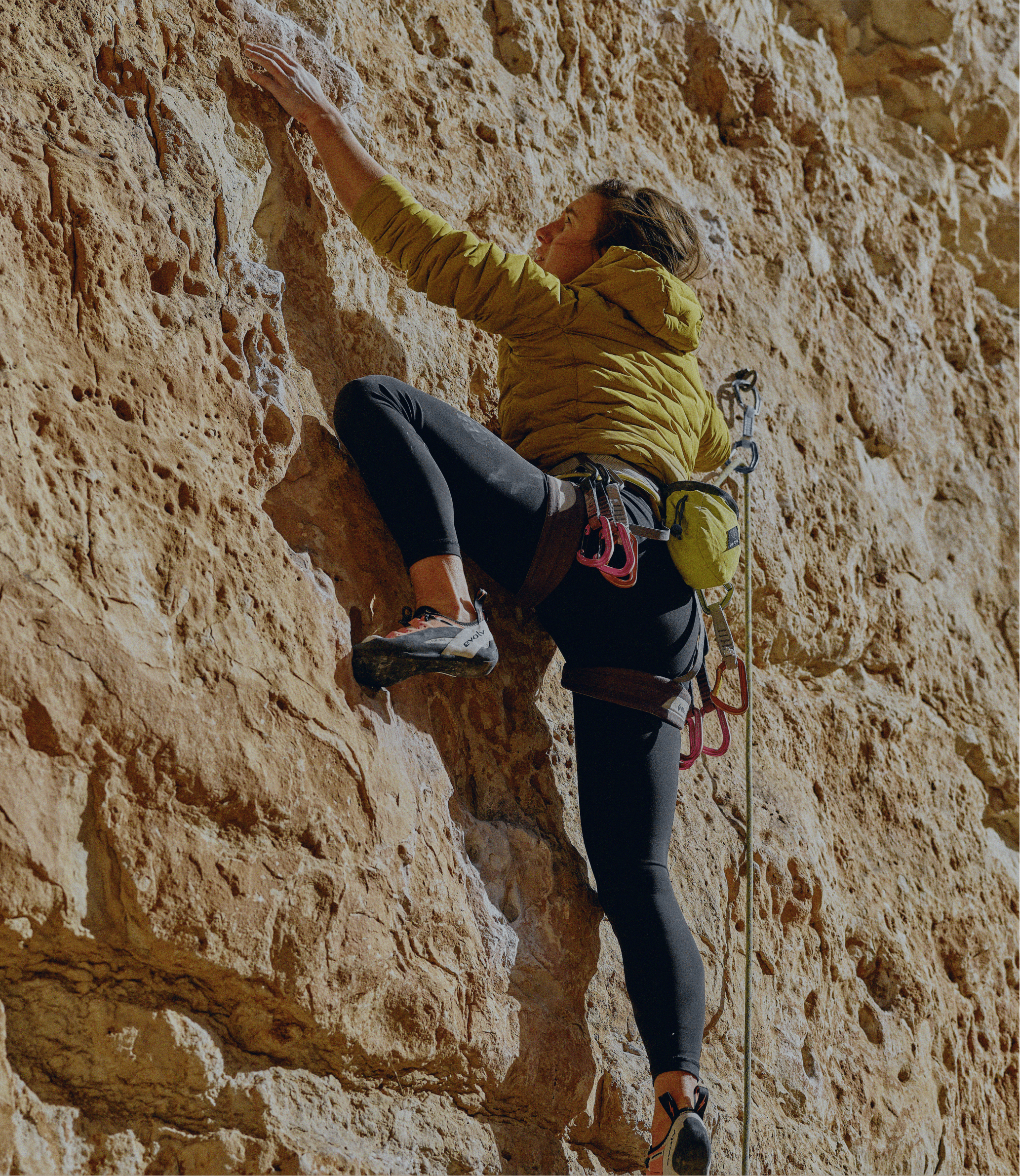 A rock climber in Evolv climbing shoes climbs outdoors.