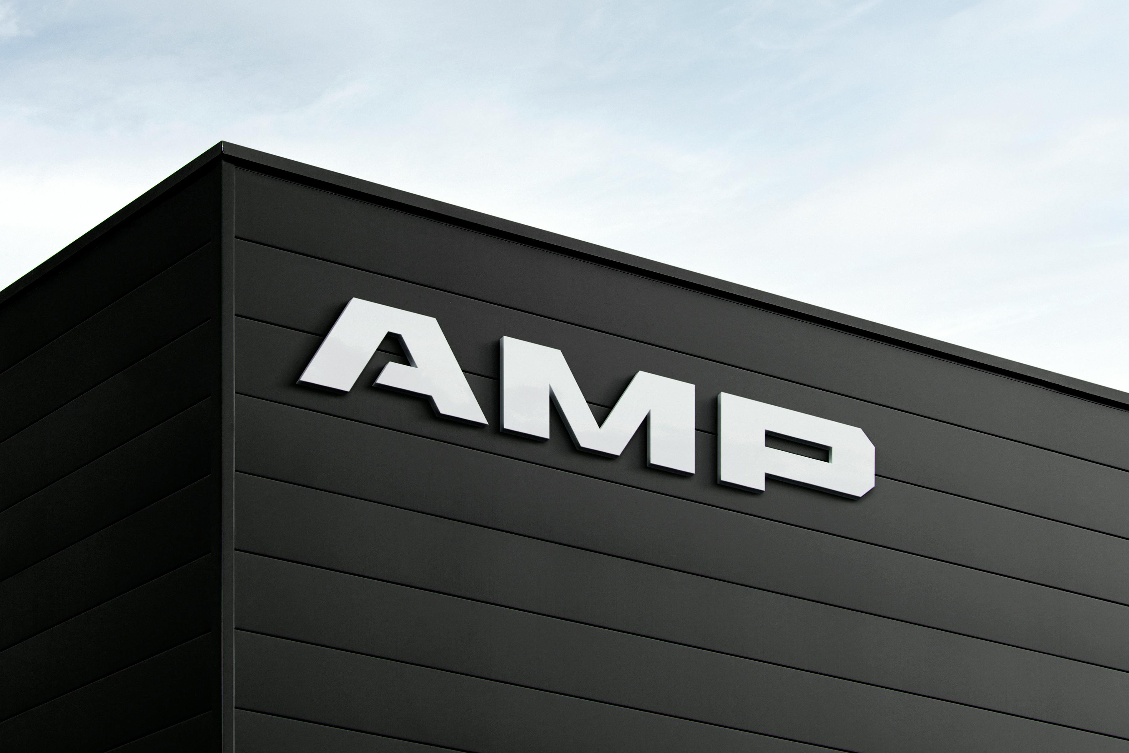 An exterior of a black building with white AMP signage overtop.