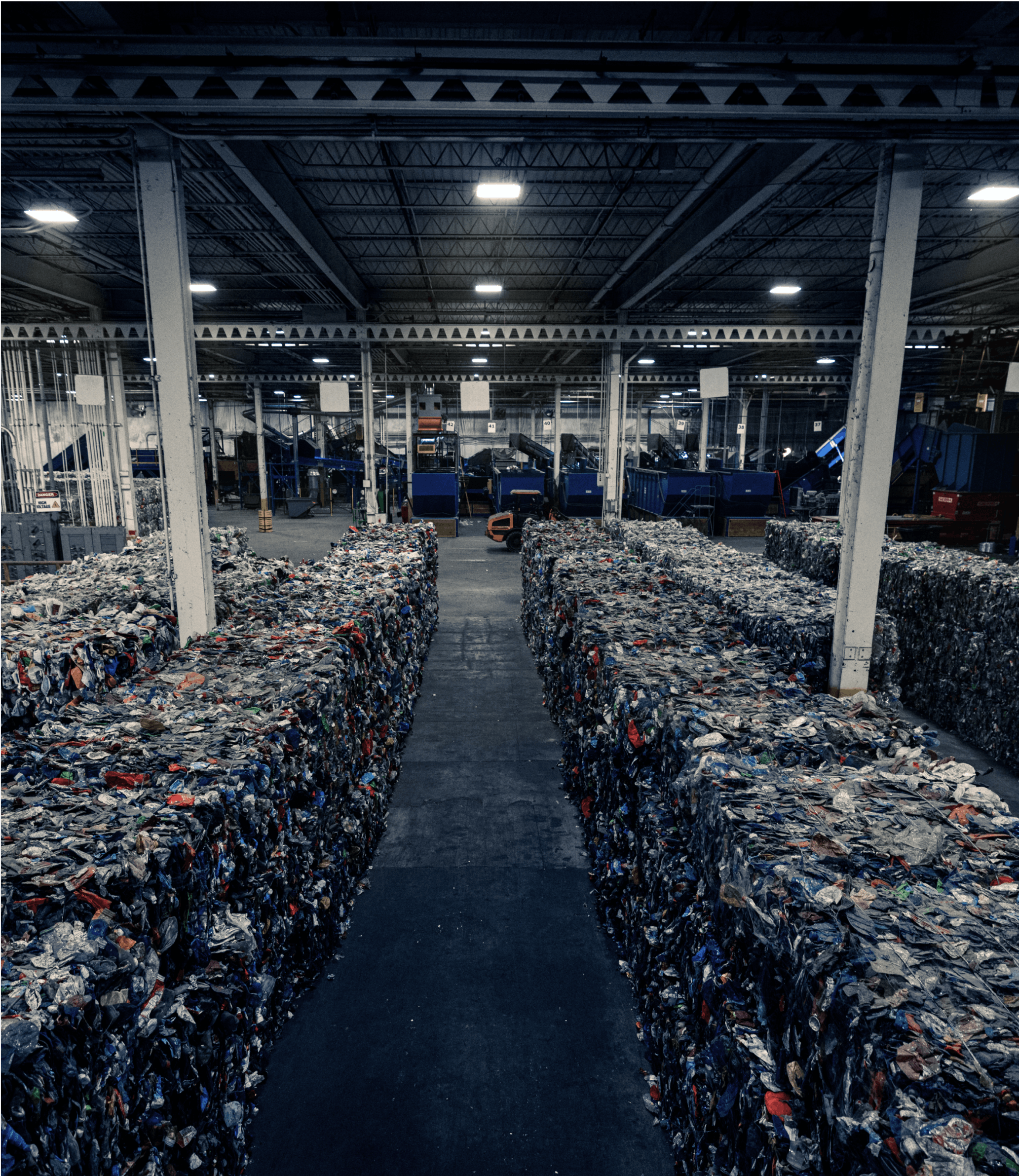 Rows of sorted recycled materials in bales inside of a waste facility.