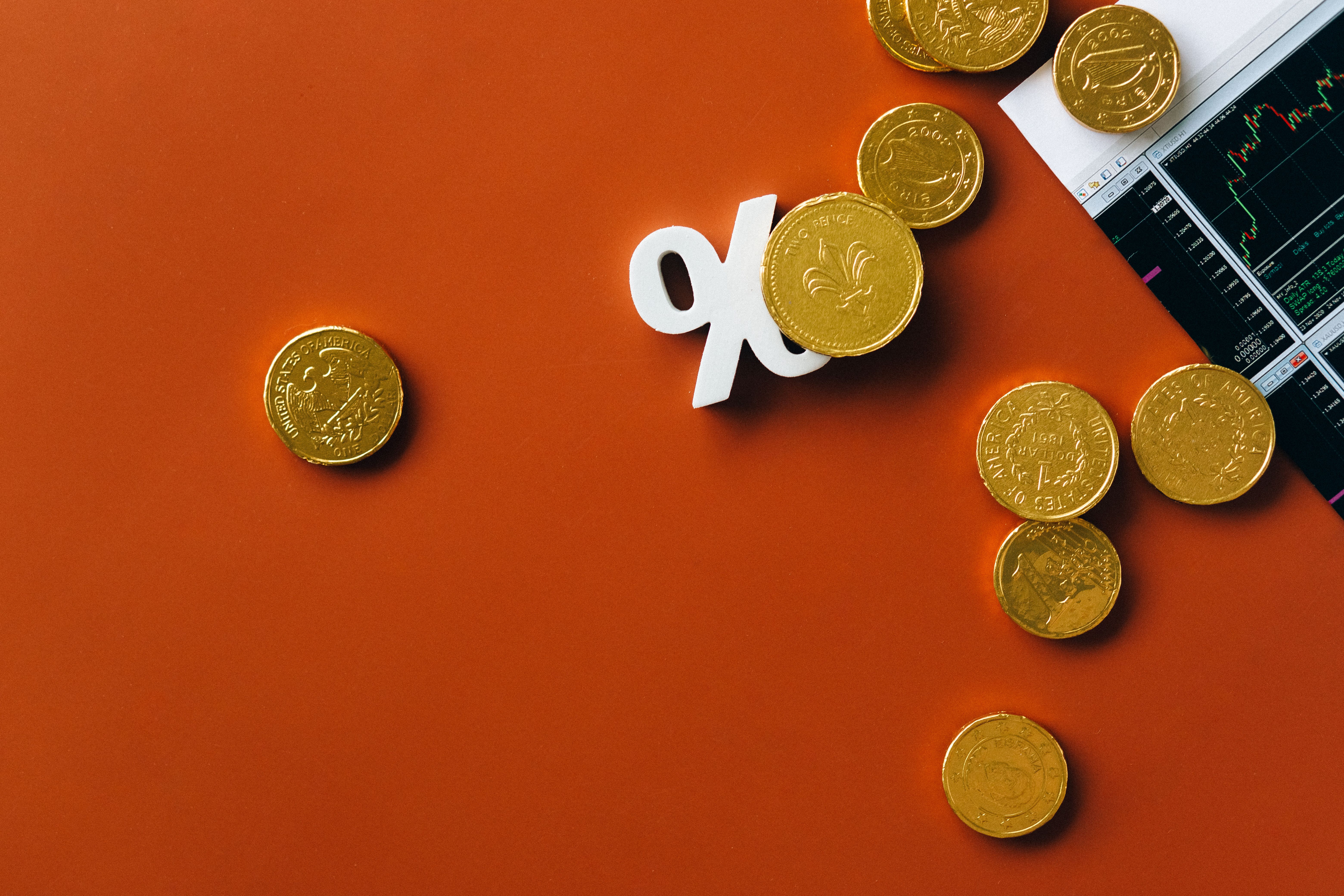 moedas e sinal de percentagem sobre fundo vermelho