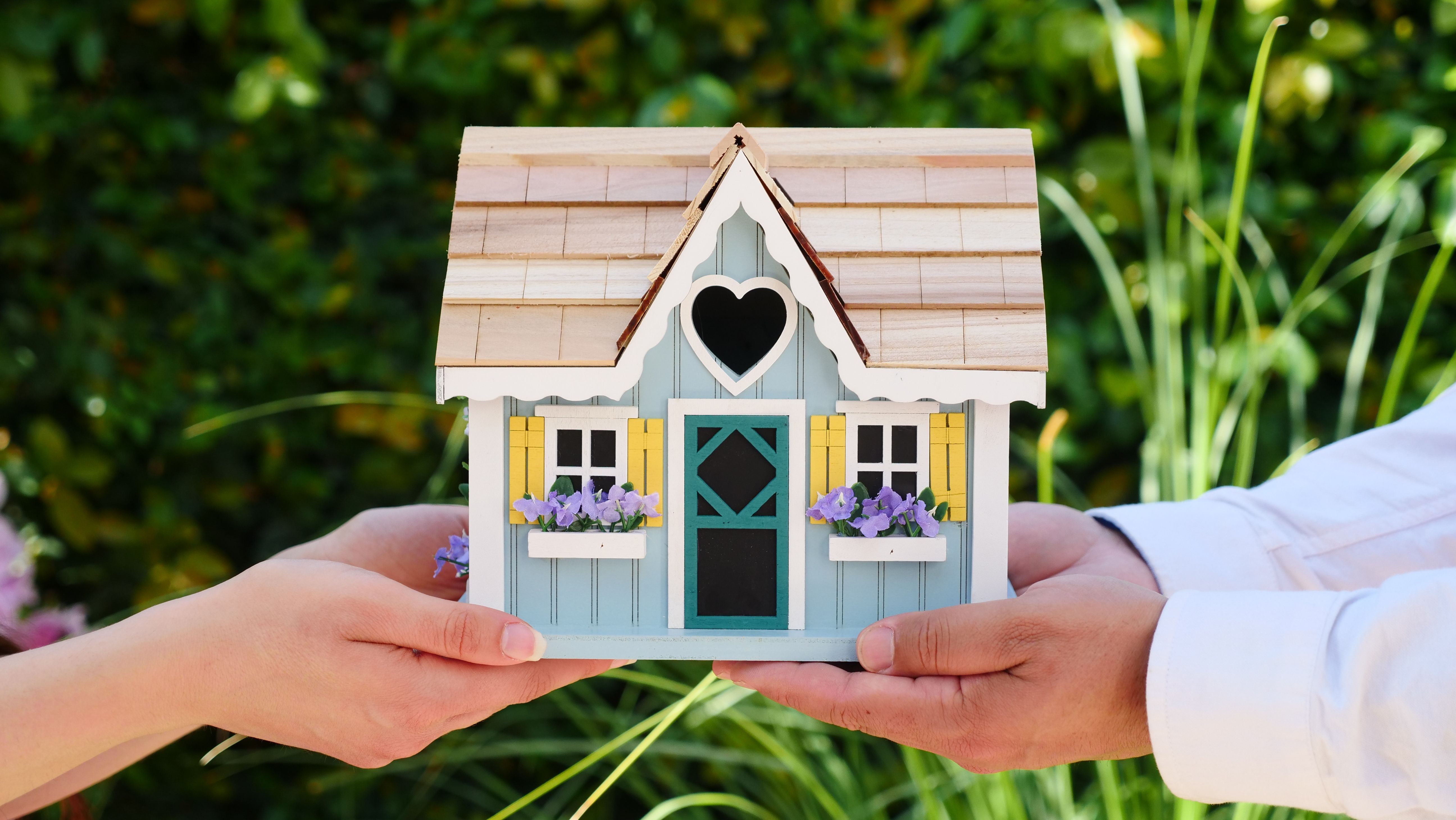 casa em miniatura e duas mãos