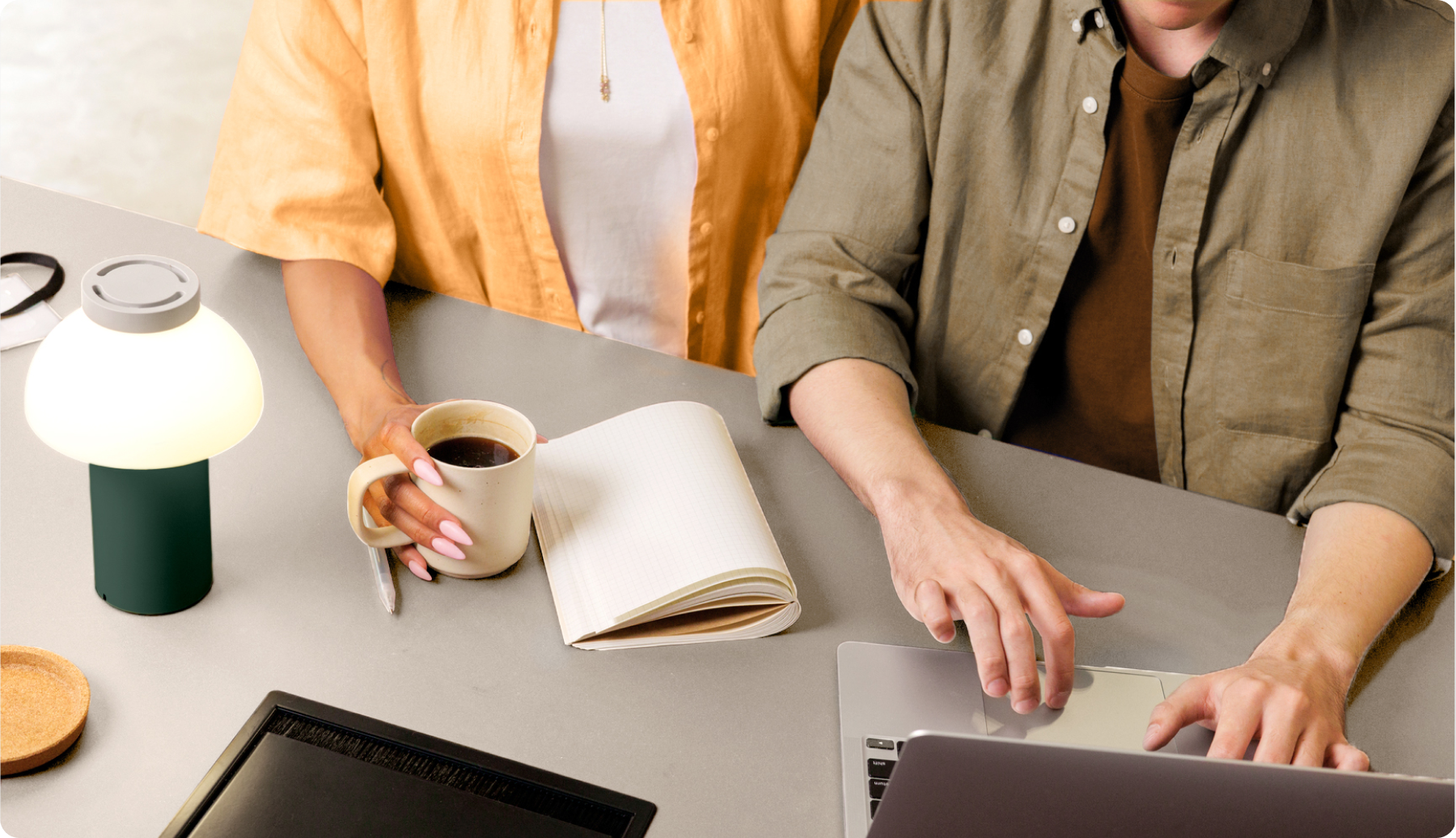 coworkers working together at desk with coffee and laptop
