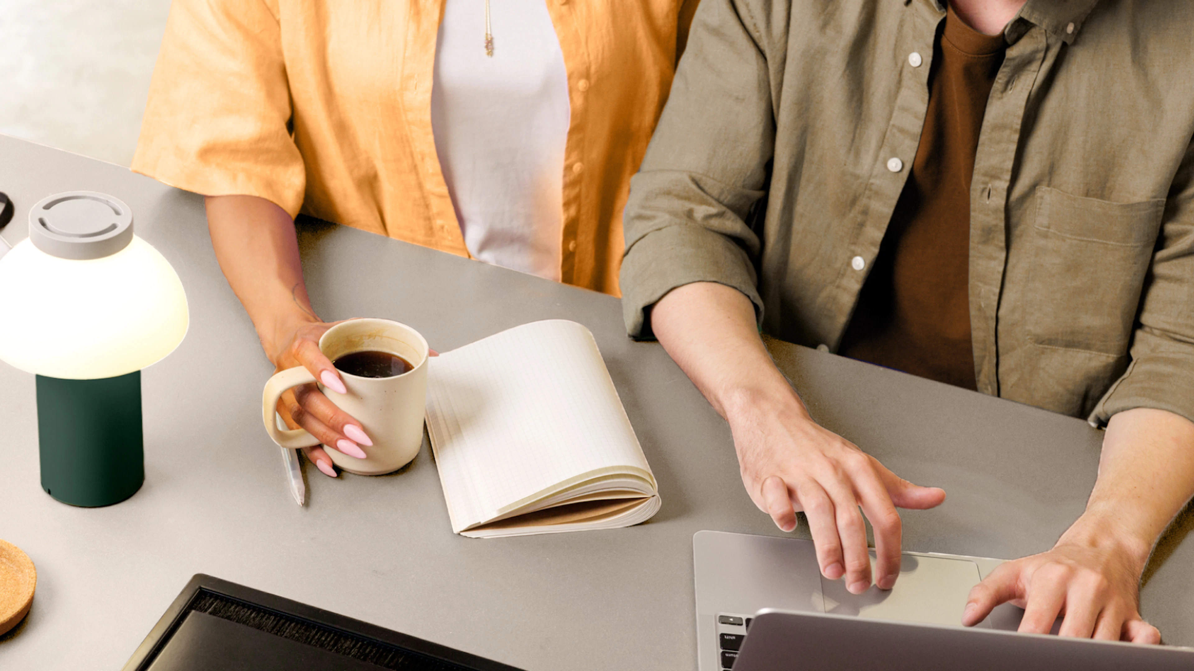 coworkers working together at desk with coffee and laptop