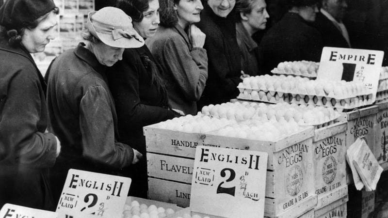 Black and white photograph of women looking at crates marked 'Canadian Eggs'