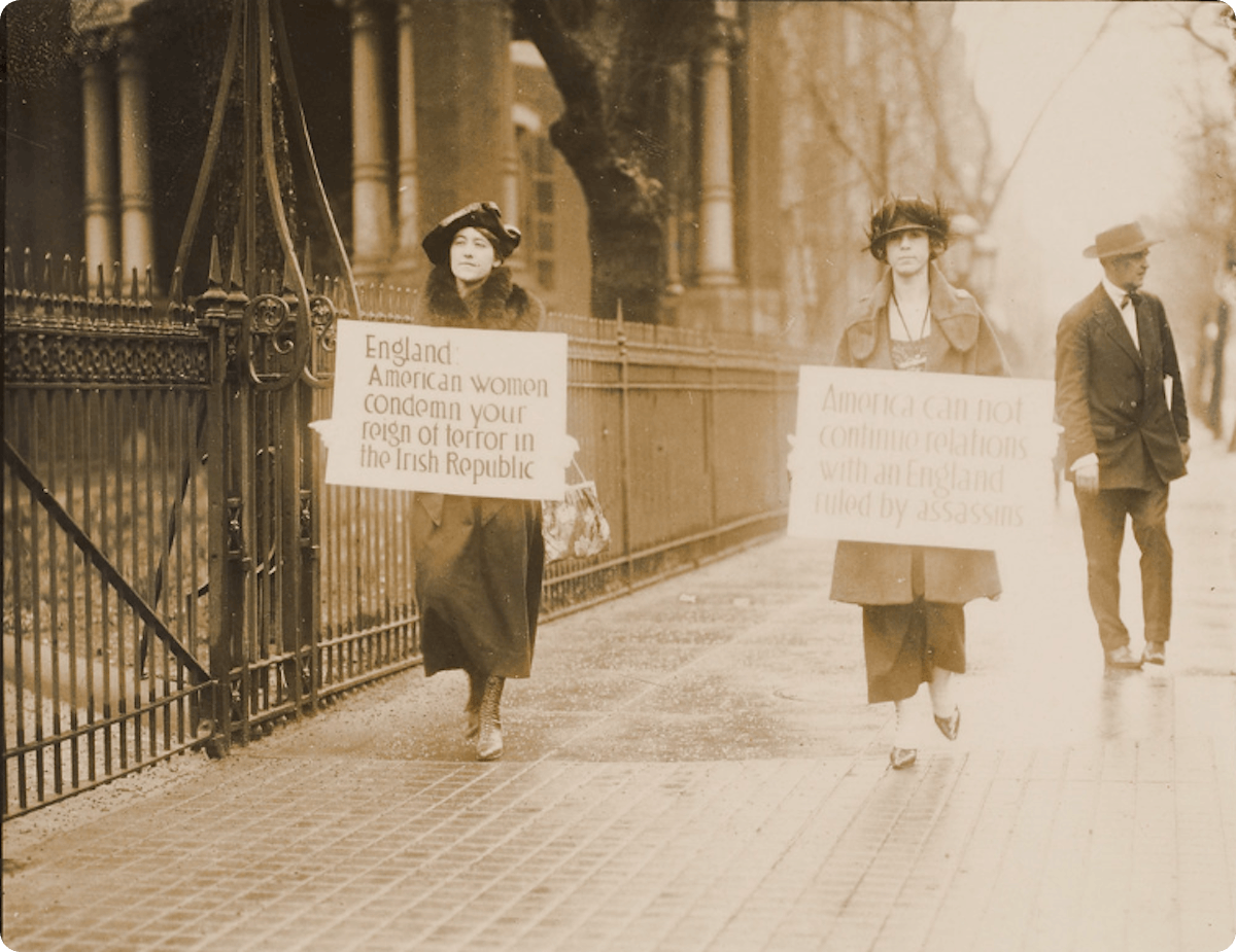 Two American Irish women hold protest placards against England's treatment of the Irish. Location and year unknown.