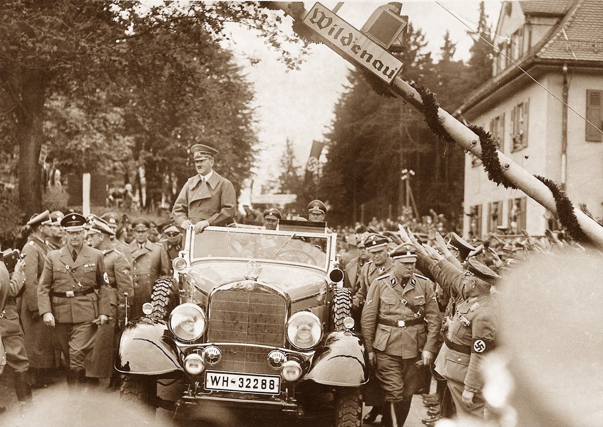 A sepia-toned photograph of Hitler enjoying a ride in his car.
