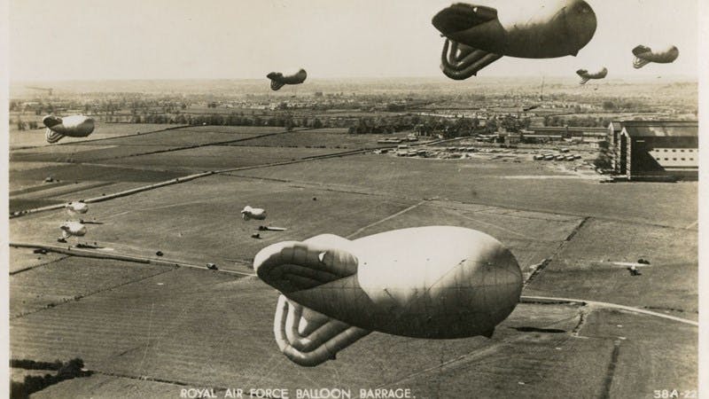 Black and white postcard of a Royal Air Force Balloon Barrage at Cardington, Bedfordshire. In the background, the airship hangars which are still there today can be seen.