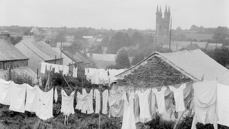 Black and white photo of the back gardens of some cottages at Buckland, near Yelverton, South Devon, England. A lot of washing is hanging on the lines.