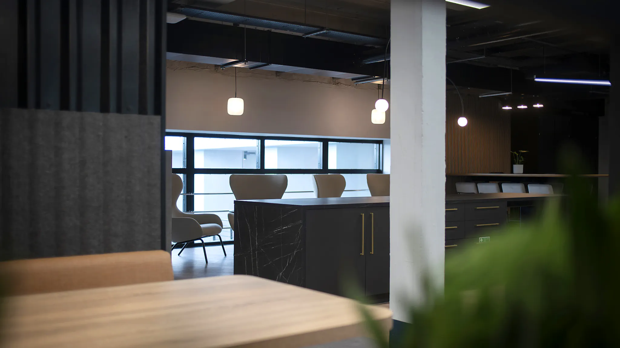 A close-up of a desk scene in an office, with soft overhead lighting and empty seats. 