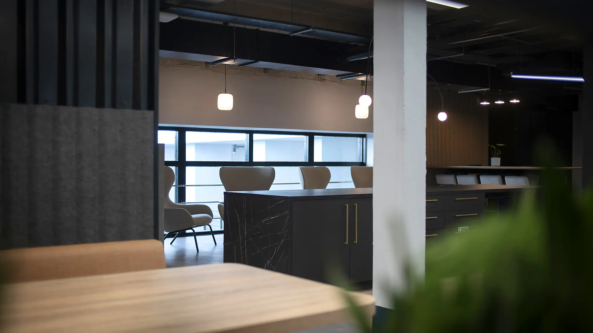 A close-up of a desk scene in an office, with soft overhead lighting and empty seats. 